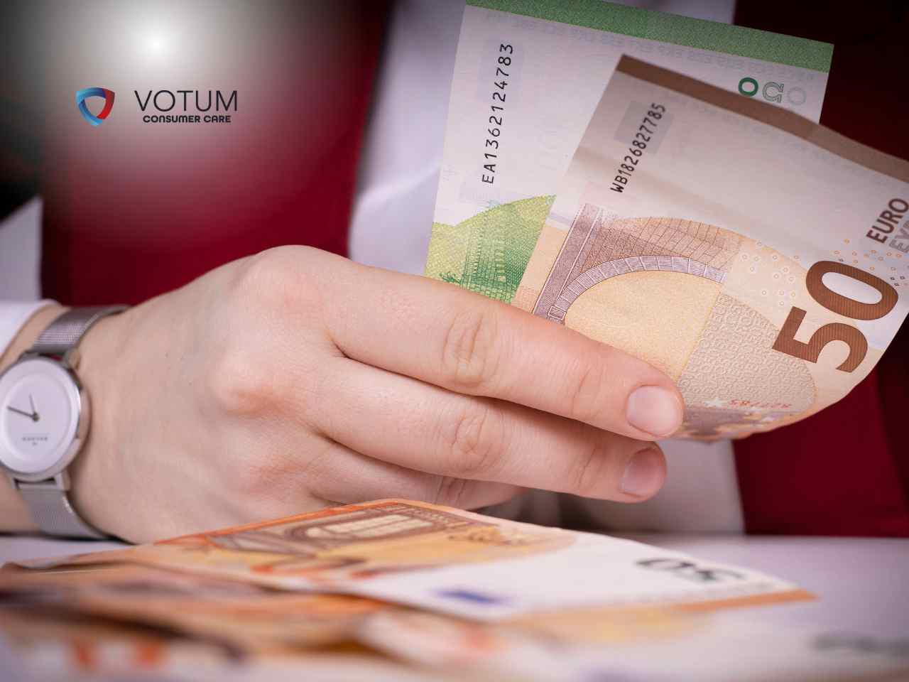 klauzule-abuzywne Osoba trzymająca w dłoniach banknoty o nominale 50 euro na tle biurka