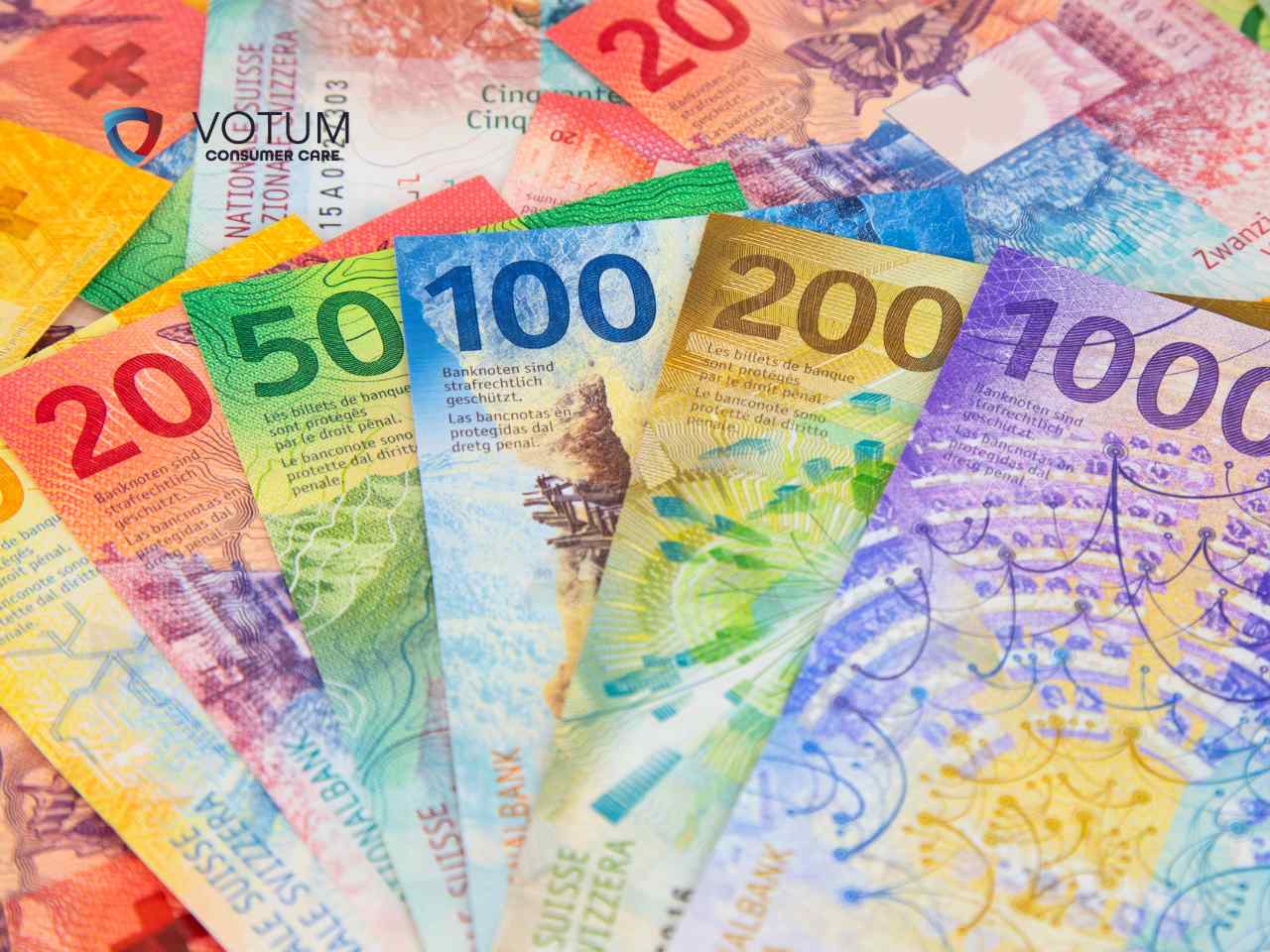 Kolorowy wachlarz nominałów franków szwajcarskich ułożony na tle innych rozrzuconych banknotów tej waluty.