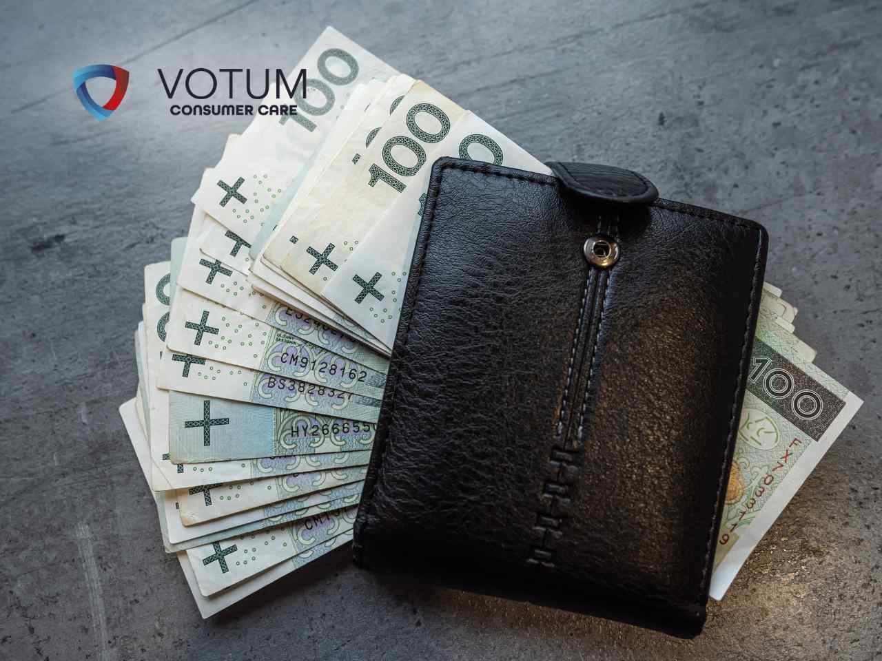 sankcja-kredytu-darmowego-alior-bank Czarny, skórzany portfel leżący na pliku banknotów o nominale stu złotych na szarym tle.