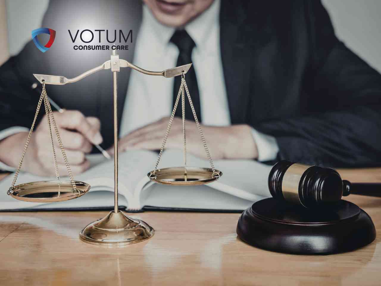 Prawnik w garniturze studiujący otwartą księgę, widziany zza wagi szalowej i młotka sędziowskiego