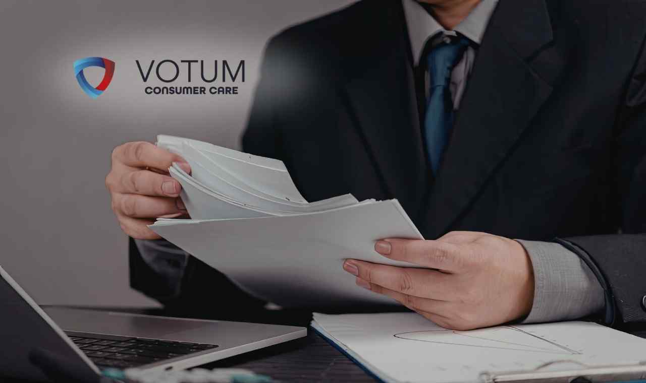 Mężczyzna w eleganckim garniturze przegląda stos białych dokumentów przy biurku z laptopem.