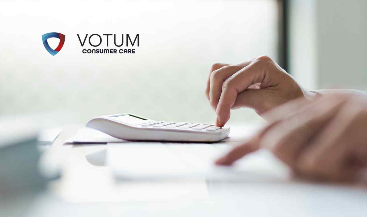 Zbliżenie na dłonie osoby korzystającej z białego kalkulatora biurowego leżącego na biurku.