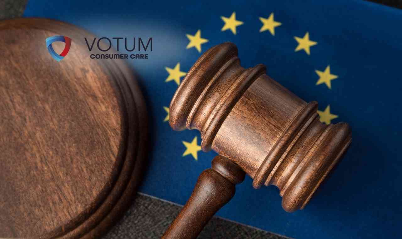 Drewniany młotek sędziowski spoczywający na niebieskiej flagi Unii Europejskiej z żółtymi gwiazdami.