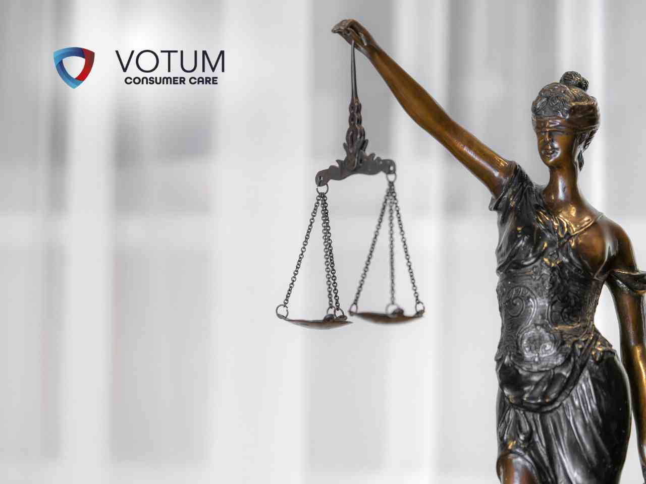 Prawnik w garniturze prezentuje dokument do podpisu klientom siedzącym przy biurku, na którym znajdują się waga szalkowa i młotek sędziowski. W lewym górnym rogu widnieje logotyp Votum Consumer Care.