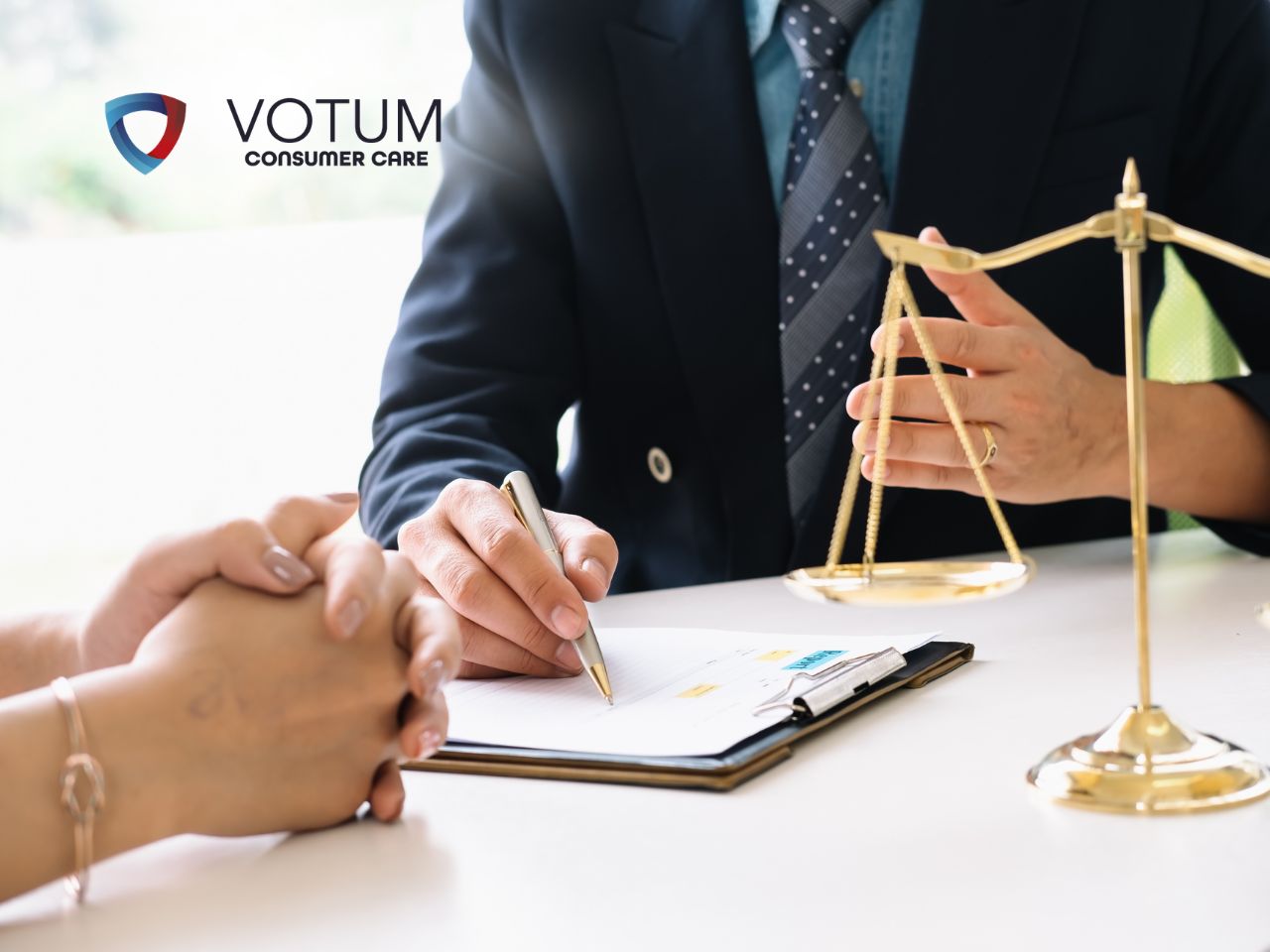 Professional signing documents at a desk with a gold scales of justice; VOTUM Consumer Care logo in the top left.