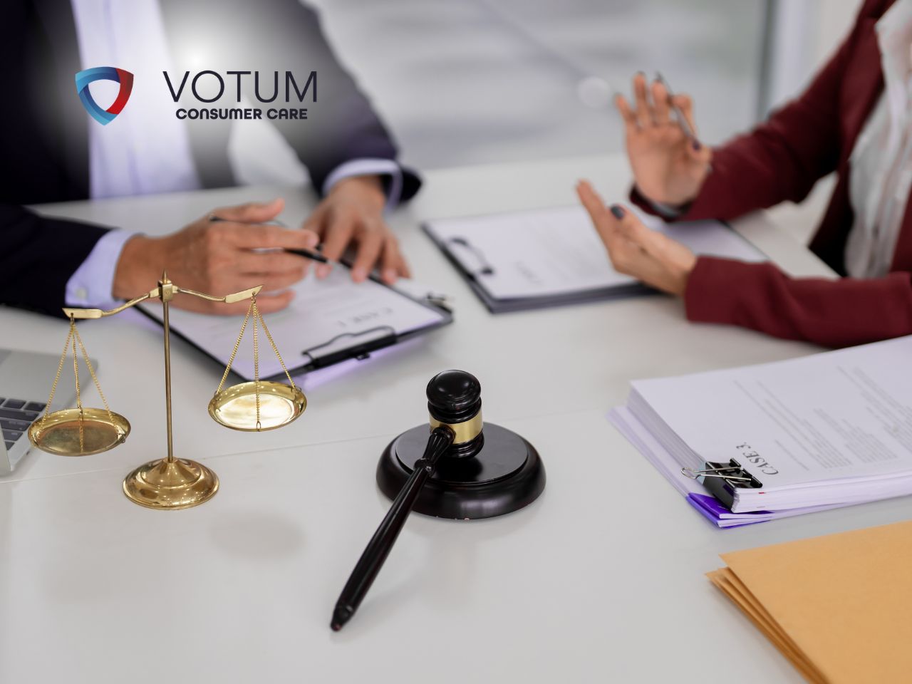 Two professionals discuss at a table with legal documents, scales of justice, and a gavel; VOTUM Consumer Care logo in the corner]","A close-up of a gavel and balancing scales on a desk during a legal meeting, with paperwork and a blurred background of two people talking.]","Legal consultation scene featuring scales, a gavel, and stacked documents, with VOTUM Consumer Care branding visible.]","Scales and gavel on a prosecutor-style desk during a meeting, illustrating law or legal services, with documents nearby.]","Business meeting image showing legal tools (gavel, scales) and contract papers, branding for VOTUM Consumer Care.]