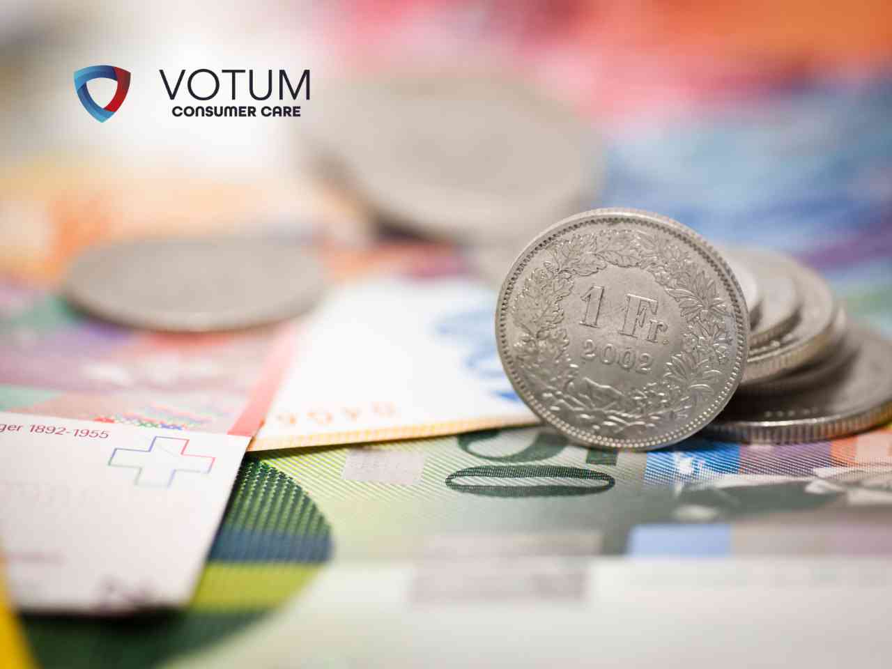 Scena w biurze lub kancelarii; po lewej stronie mężczyzna w ciemnym garniturze i okularach przekazuje dokument kobiecie w beżowej marynarce. W tle widoczny jest drugi mężczyzna, który z niedowierzaniem trzyma się za głowę. Na stole leżą teczki z aktami oraz gazeta.