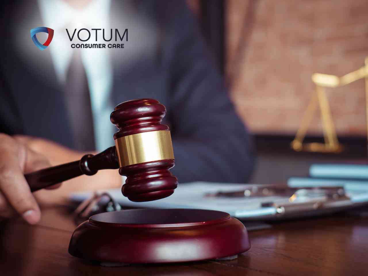 sankcja-kredytu-darmowego-krok-po-kroku Gavel resting on a wooden table with a blurred legal setting and the VOTUM Consumer Care logo in view.