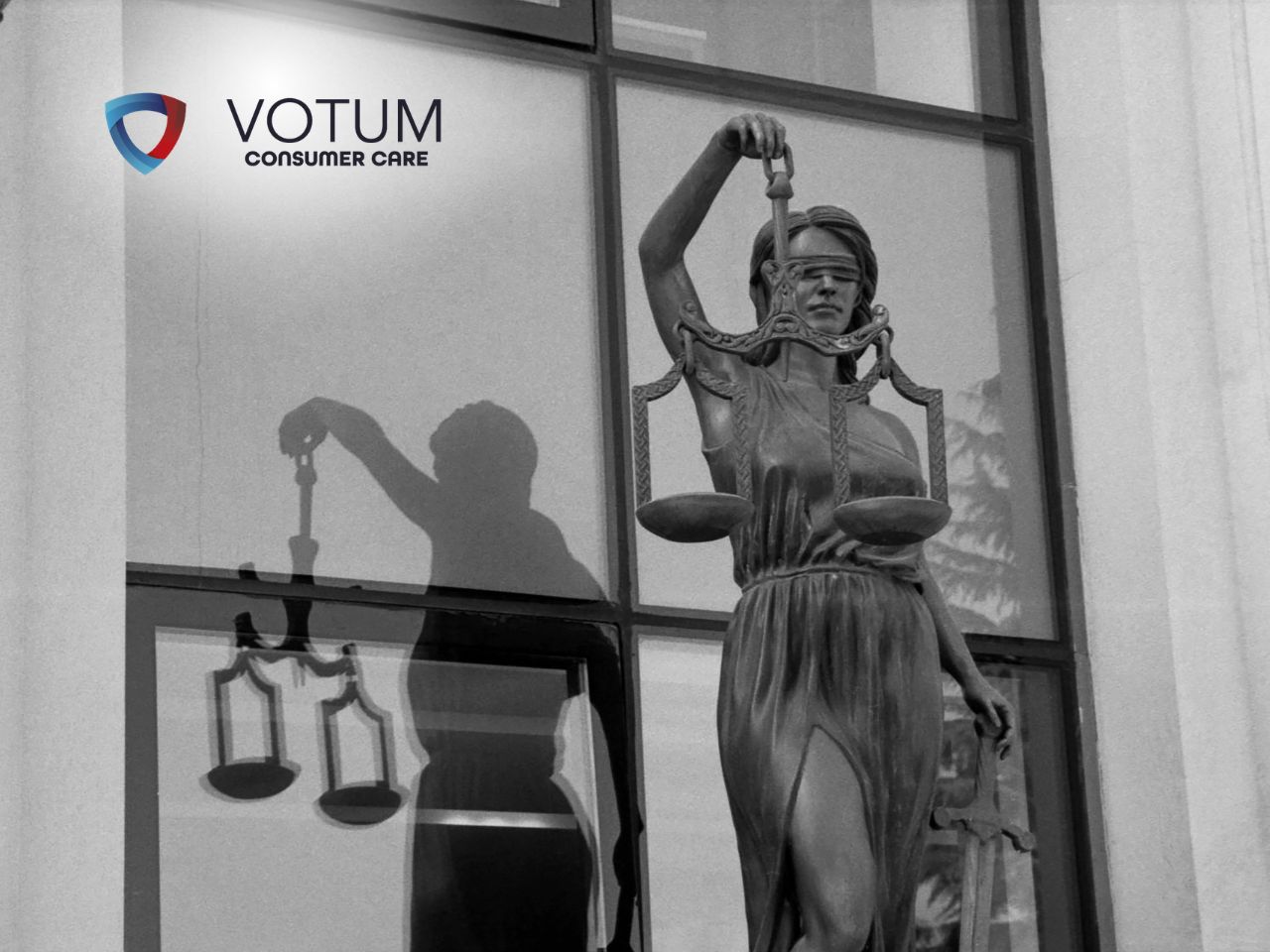uniewaznienie-splaconego-kredytu-frankowego Statue of Lady Justice with scales and sword, standing beside a glass storefront displaying the VOTUM Consumer Care logo.