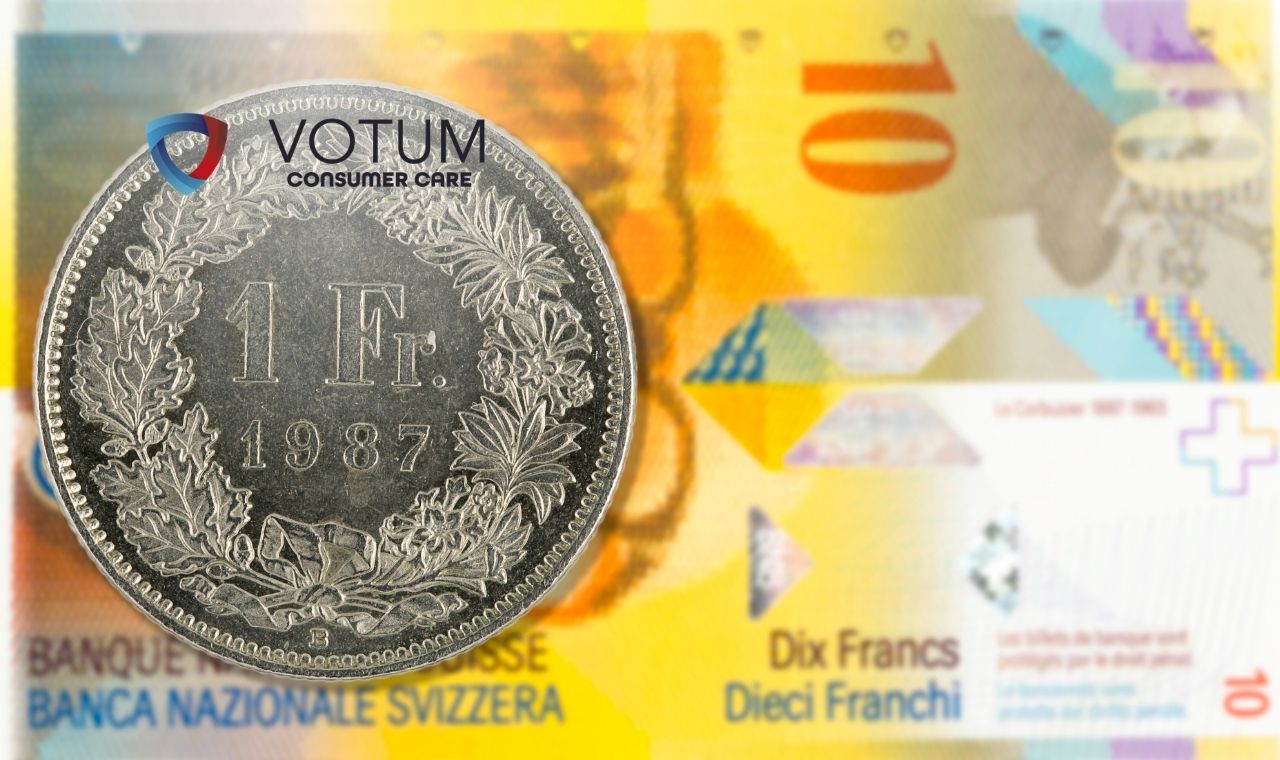 Zbliżenie na srebrne monety franka szwajcarskiego (CHF) rozrzucone na jasnej powierzchni. Na centralnej monecie o nominale 1 franka widoczna jest data 1968, a w tle moneta z rokiem 2016