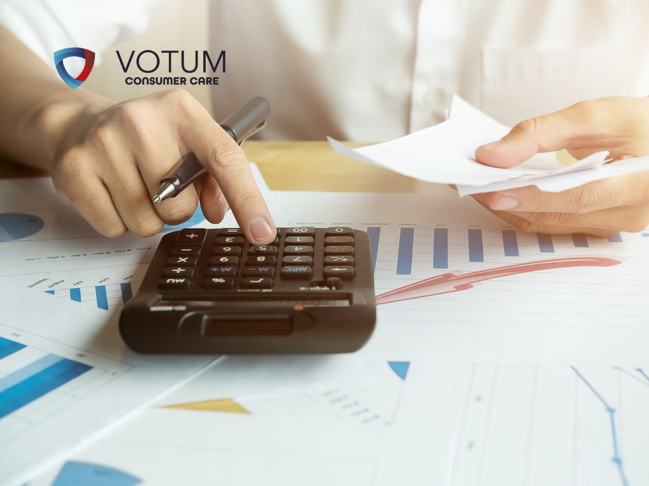 Person using a calculator to review financial charts and documents, with a VOTUM Consumer Care logo in the top-left corner