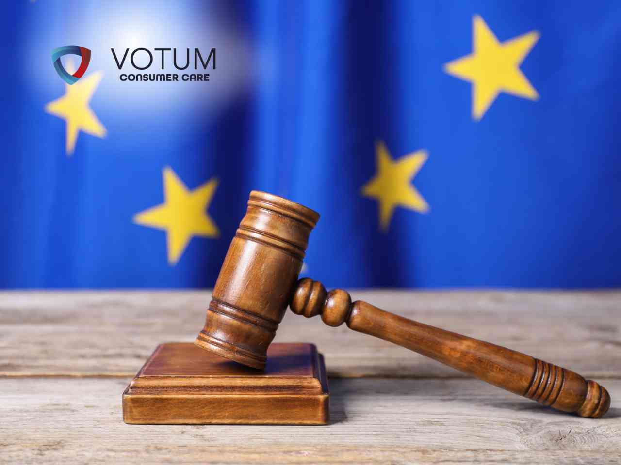 Scena w biurze lub kancelarii; po lewej stronie mężczyzna w ciemnym garniturze i okularach przekazuje dokument kobiecie w beżowej marynarce. W tle widoczny jest drugi mężczyzna, który z niedowierzaniem trzyma się za głowę. Na stole leżą teczki z aktami oraz gazeta.