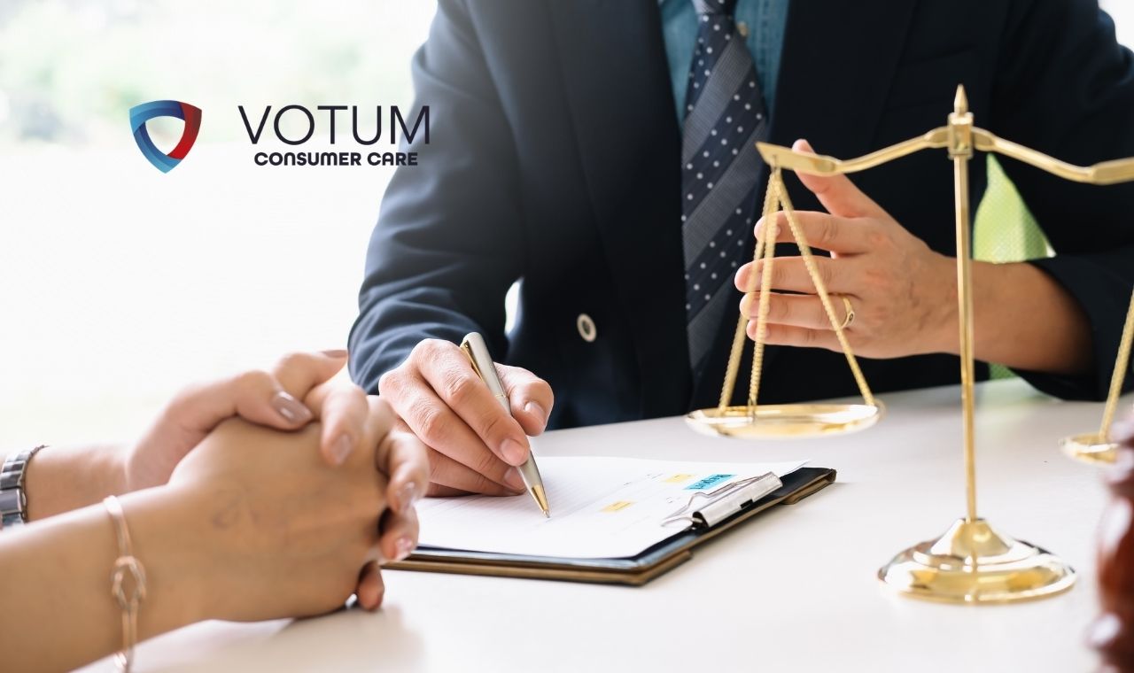 Person signing a document at a desk with a silver laptop nearby and the VOTUM Consumer Care logo visible on the left.